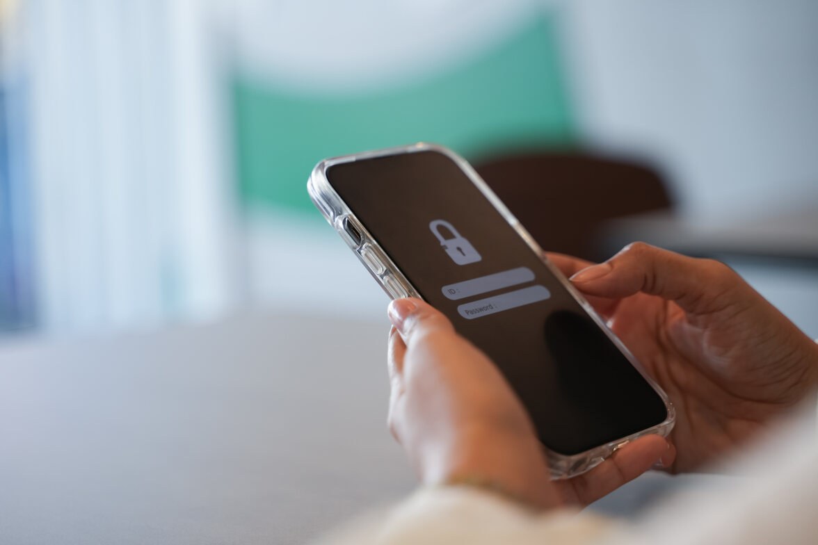 Una mano tiene uno smartphone che mostra un accesso protetto