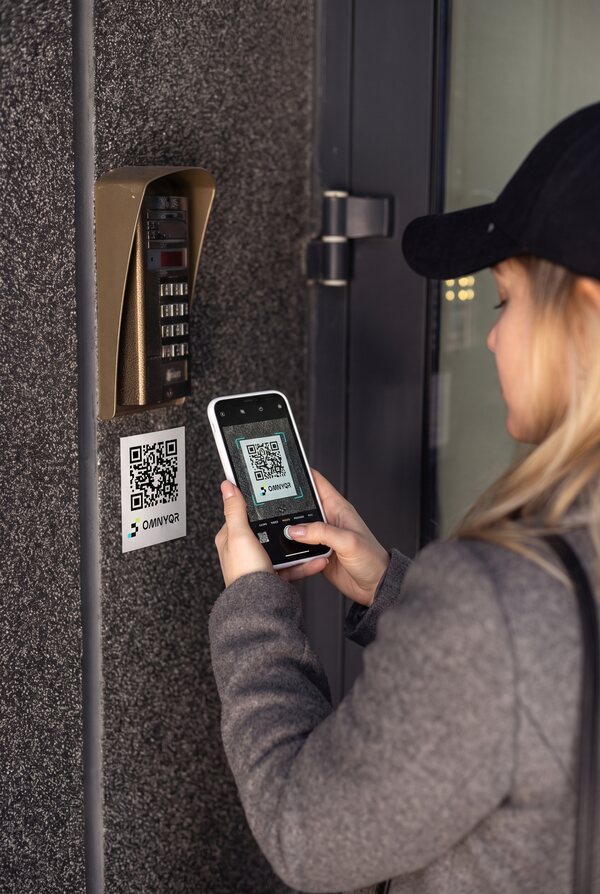 Una persona inquadra col telefono un tag QR OmnyQR su un citofono
