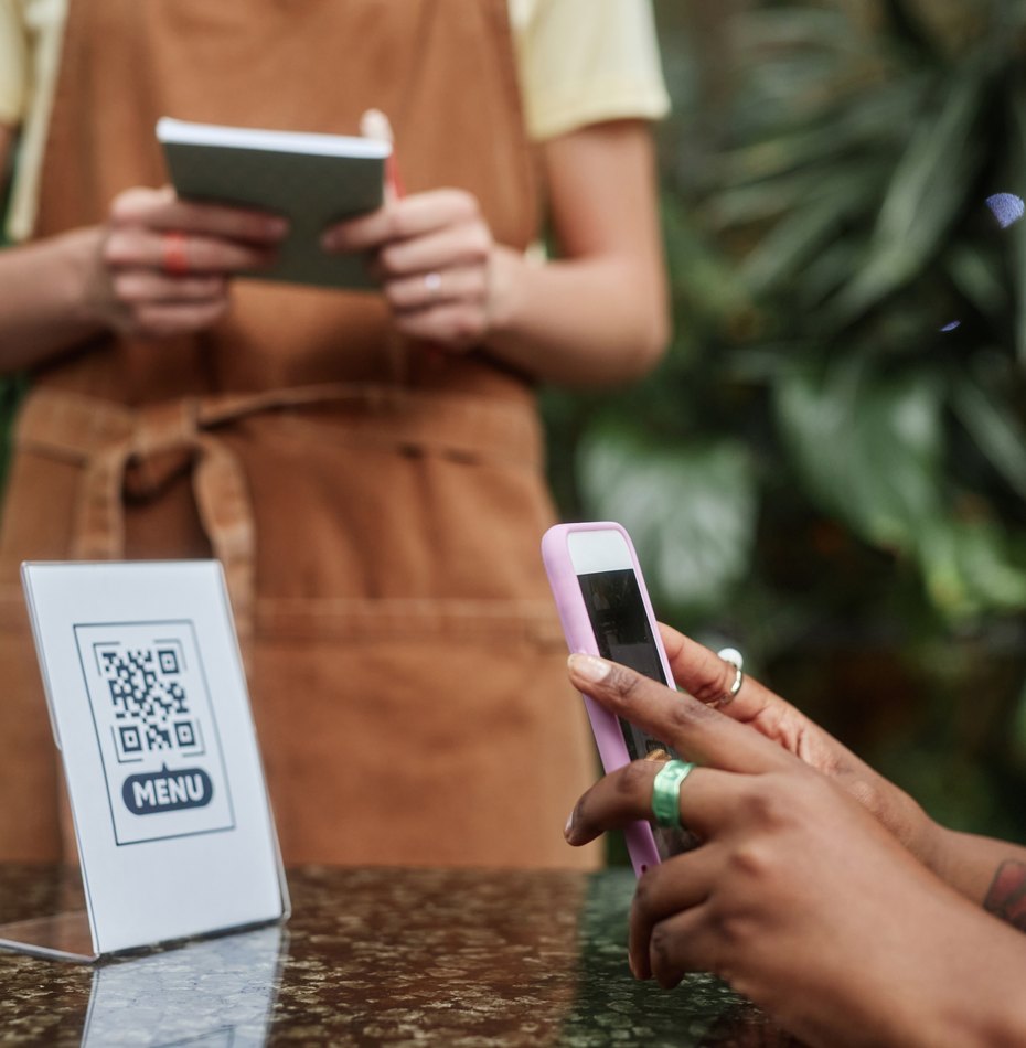 Una cliente inquadra il QR del menù al banco di un locale